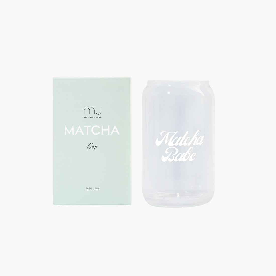 Clear can-shaped Matcha Babe glass with white script lettering beside its mint-green Matcha Union box, designed for iced matcha and cold lattes.