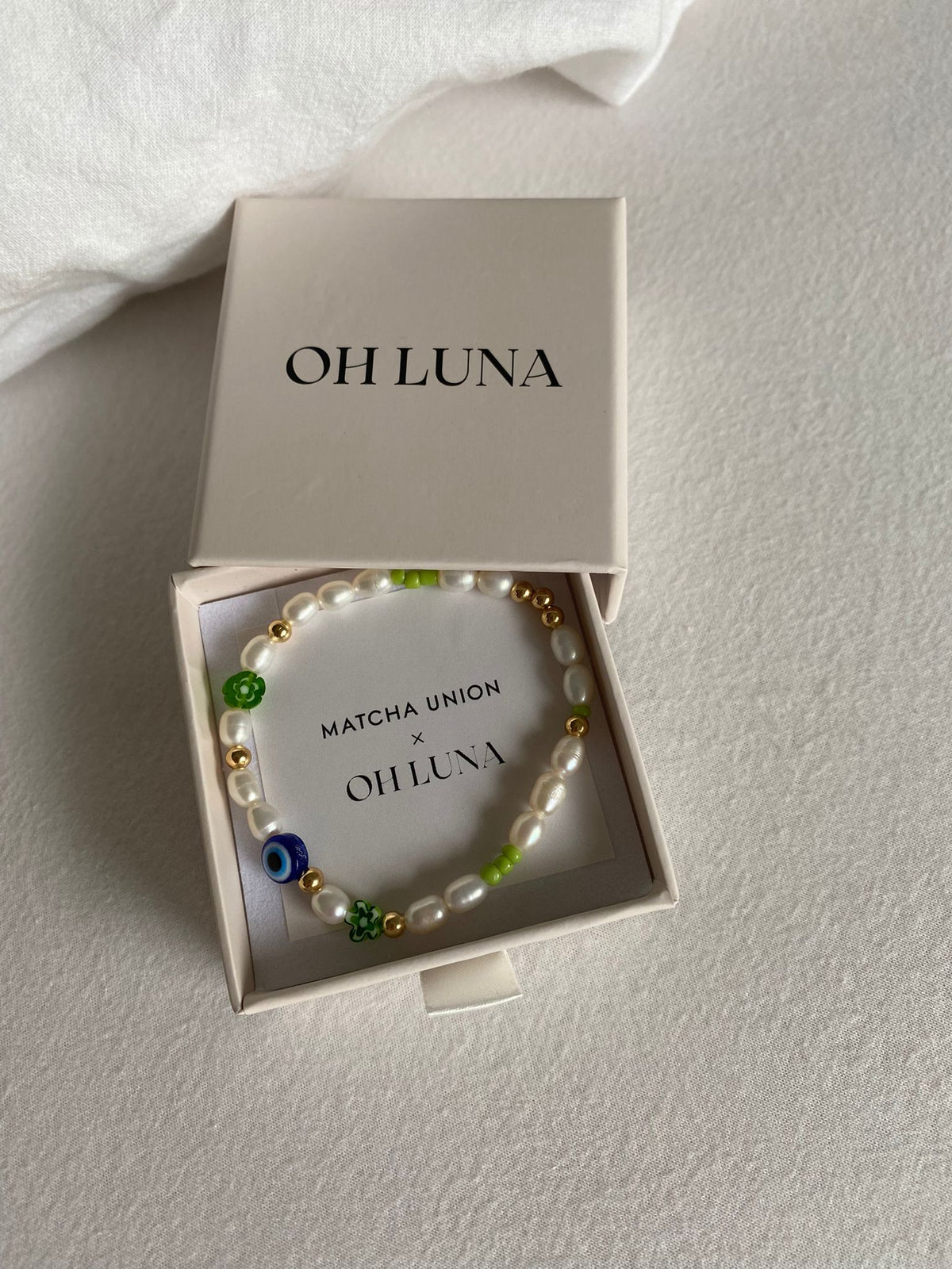 Matcha Magic bracelet displayed in an open Oh Luna jewellery box with a Matcha Union x Oh Luna insert, showing its pearl, gold and colourful glass beads.