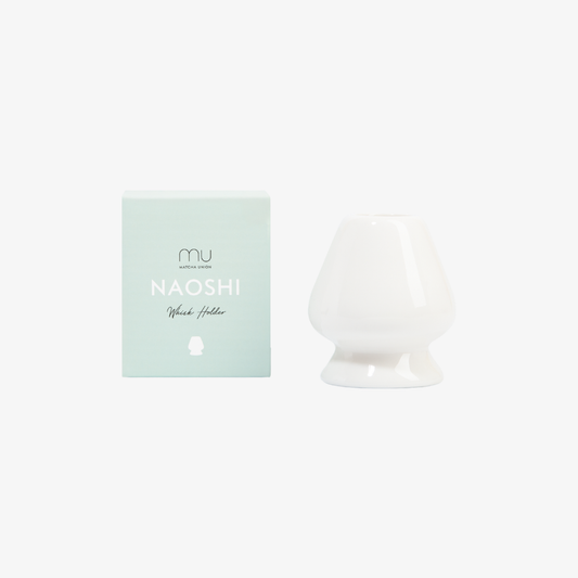 White ceramic Matcha Union whisk holder beside its mint-green Naoshi box, shaped to keep bamboo whisk prongs fanned out between uses.